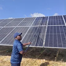 Technician cleaning dusty rooftop solar panels