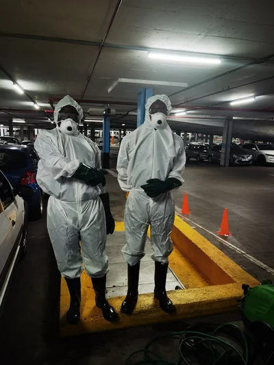Technicians in full protective suits ready for a grease trap clean in a parking basement