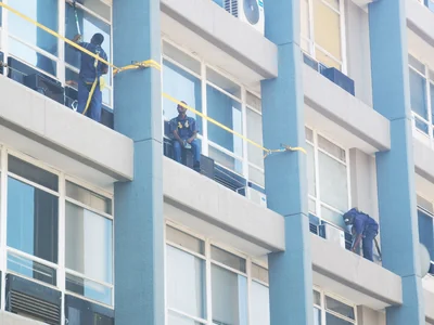 Window cleaners in safety harnesses cleaning high rise office windows