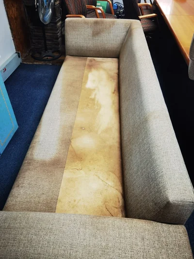 Heavily soiled grey fabric couch before upholstery deep cleaning