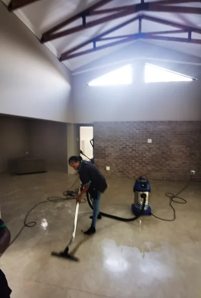 Cleaner using a wet vacuum on a polished concrete floor in a new build