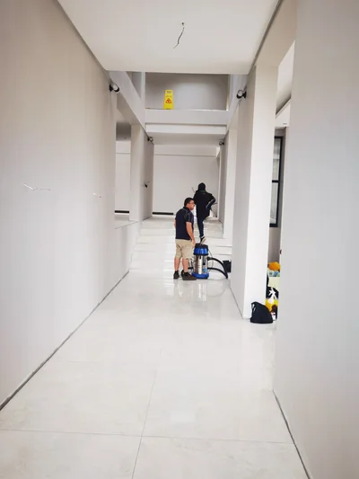 Team cleaning tiled corridor floors during a post construction handover