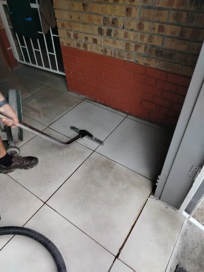 Operator scrubbing entrance floor tiles with a rotary machine and wet vacuum